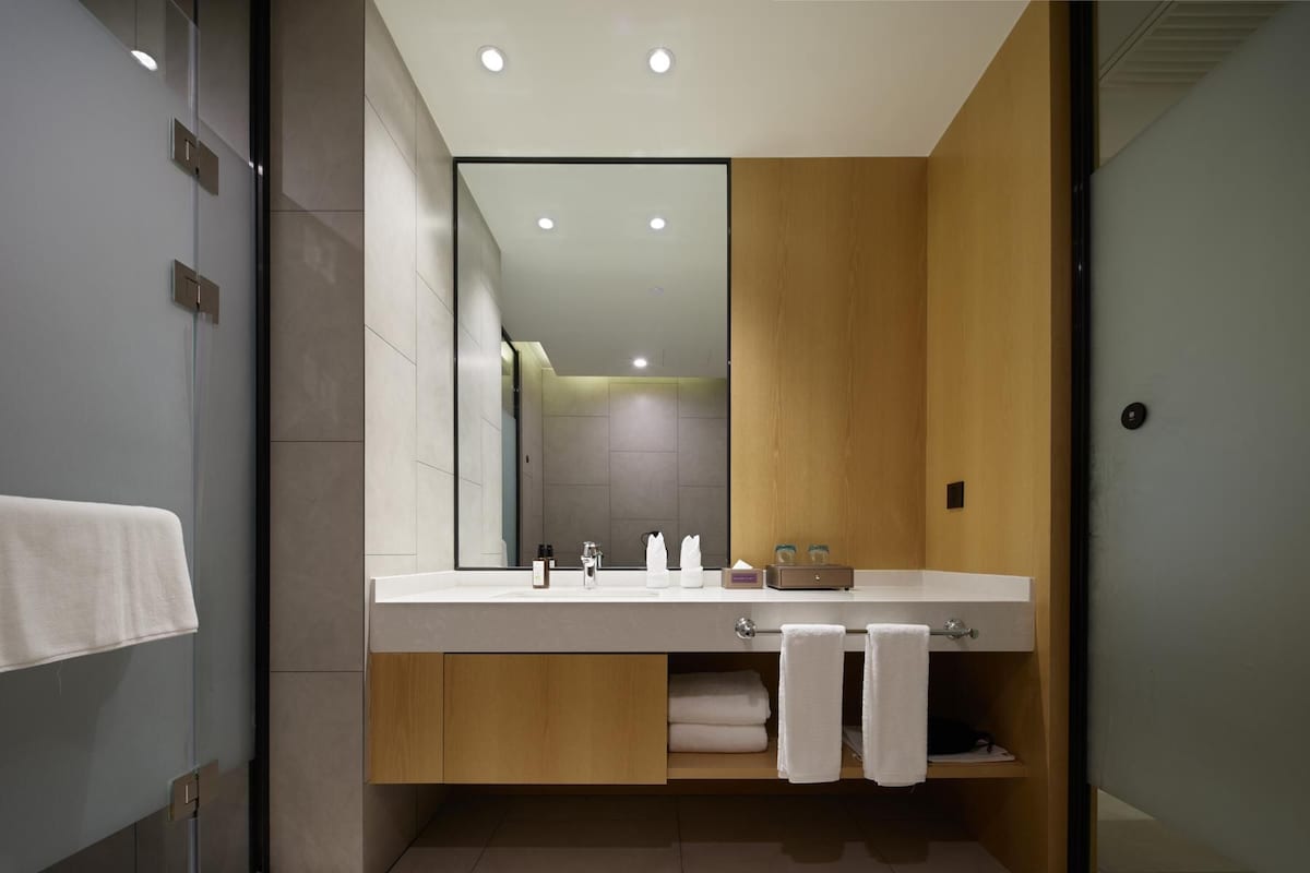 A modern bathroom with a large mirror, a wooden vanity, and a glass shower enclosure.
