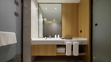 A modern bathroom with a large mirror, a wooden vanity, and a glass shower enclosure.