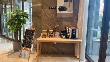 A modern interior with a coffee station, a chalkboard sign, and a large window.