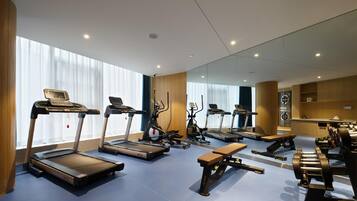 Une salle de sport moderne équipée de tapis de course, de vélos elliptiques et de bancs de musculation.