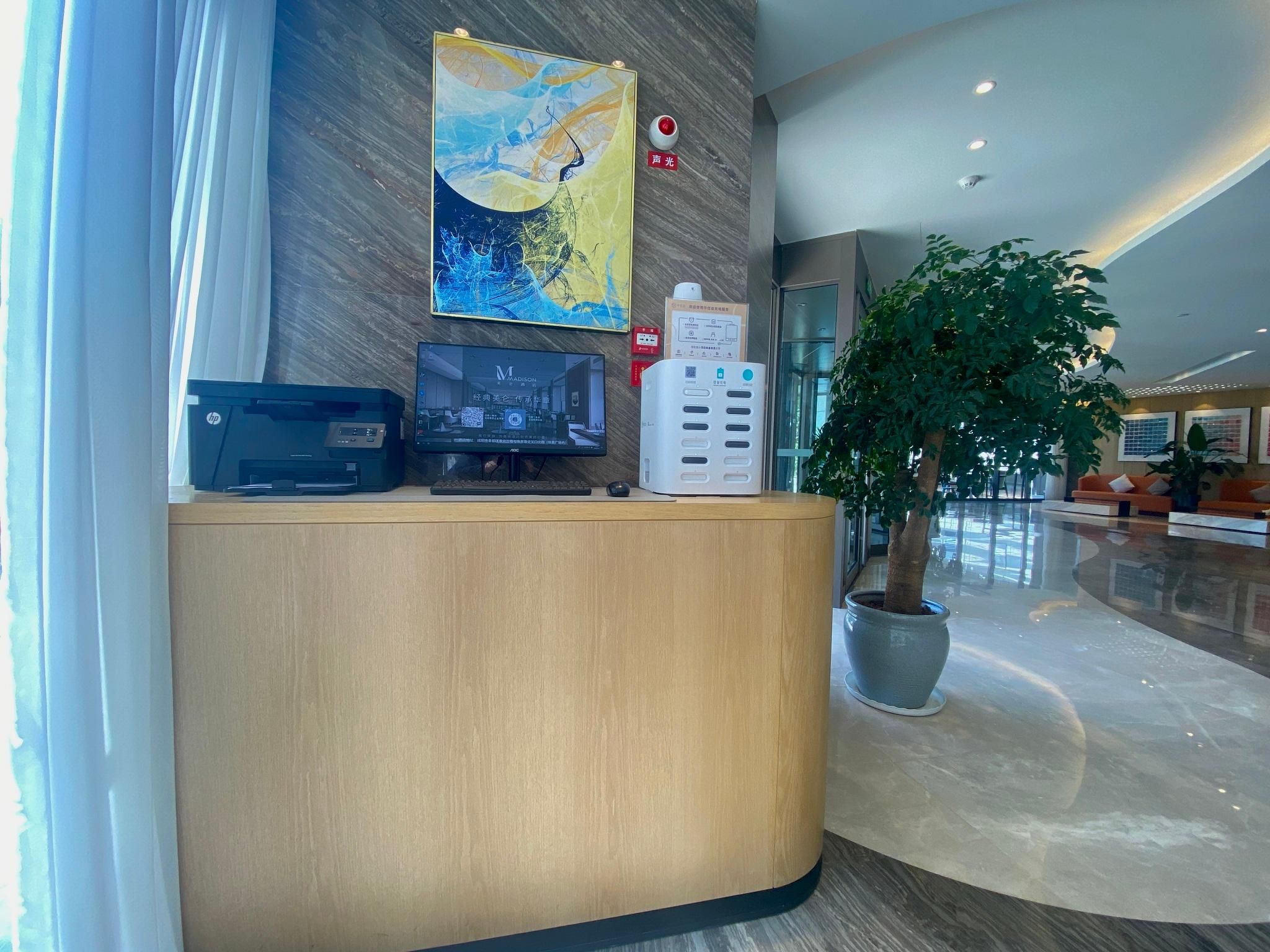 Una reception con un computer, una stampante e una pianta.