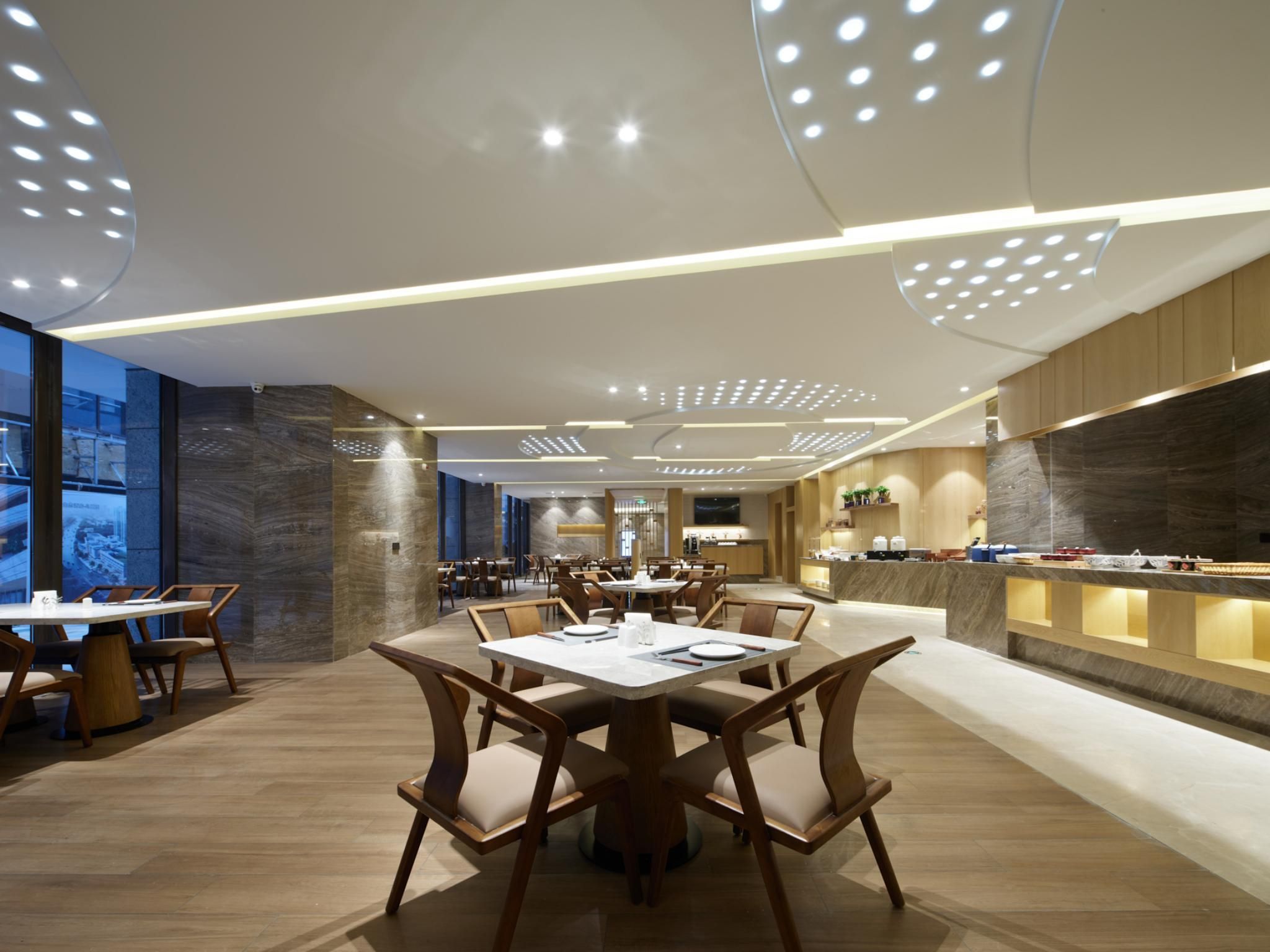 Un comedor moderno con mesas y sillas redondas, una barra de cocina y un ventanal grande.