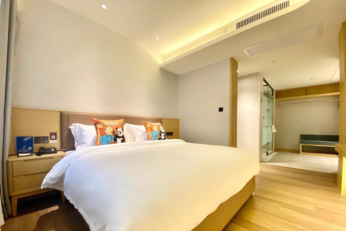 Ein modernes Hotelzimmer mit einem großen Bett, Nachttischen, einem Schreibtisch und einem begehbaren Kleiderschrank.