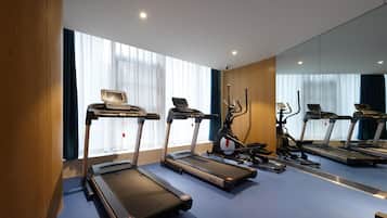 A gym with treadmills, an elliptical, and a stationary bike, with large windows and a mirror wall.