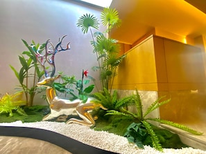 A decorative indoor garden with a reflective sculpture, lush green plants, and a pebble-lined foreground. - Madison Hotel Xianyang Zhuquan Road Wanda Plaza (Xianyang)