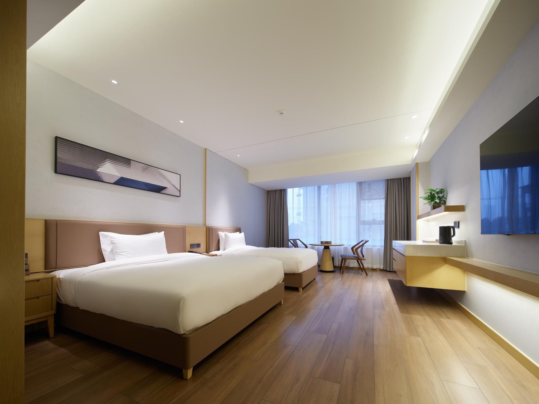 A modern hotel room with a large bed, a desk, and a TV.