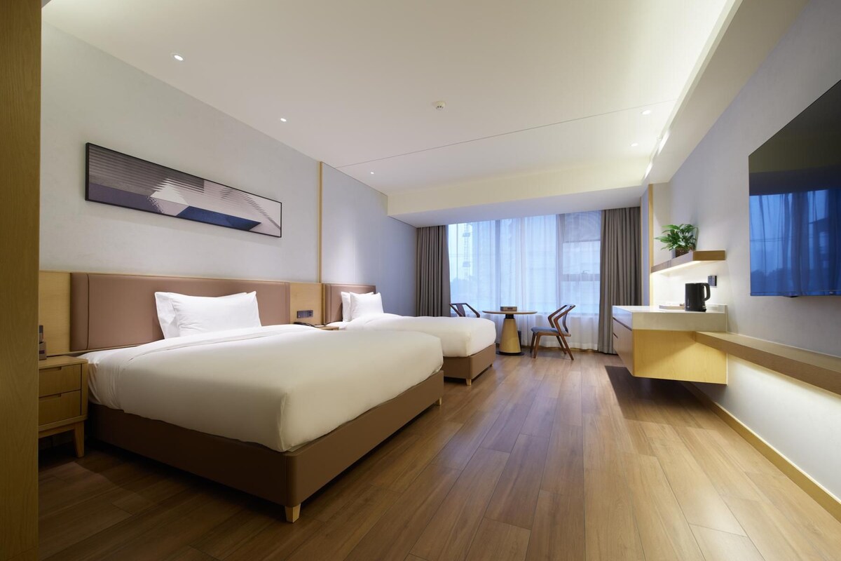 A modern hotel room with a large bed, a desk, and a TV.