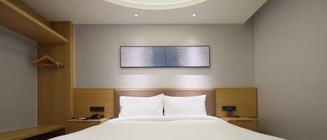 A modern hotel room with a large bed, wooden headboard, bedside tables, a wall-mounted artwork, and a circular skylight.