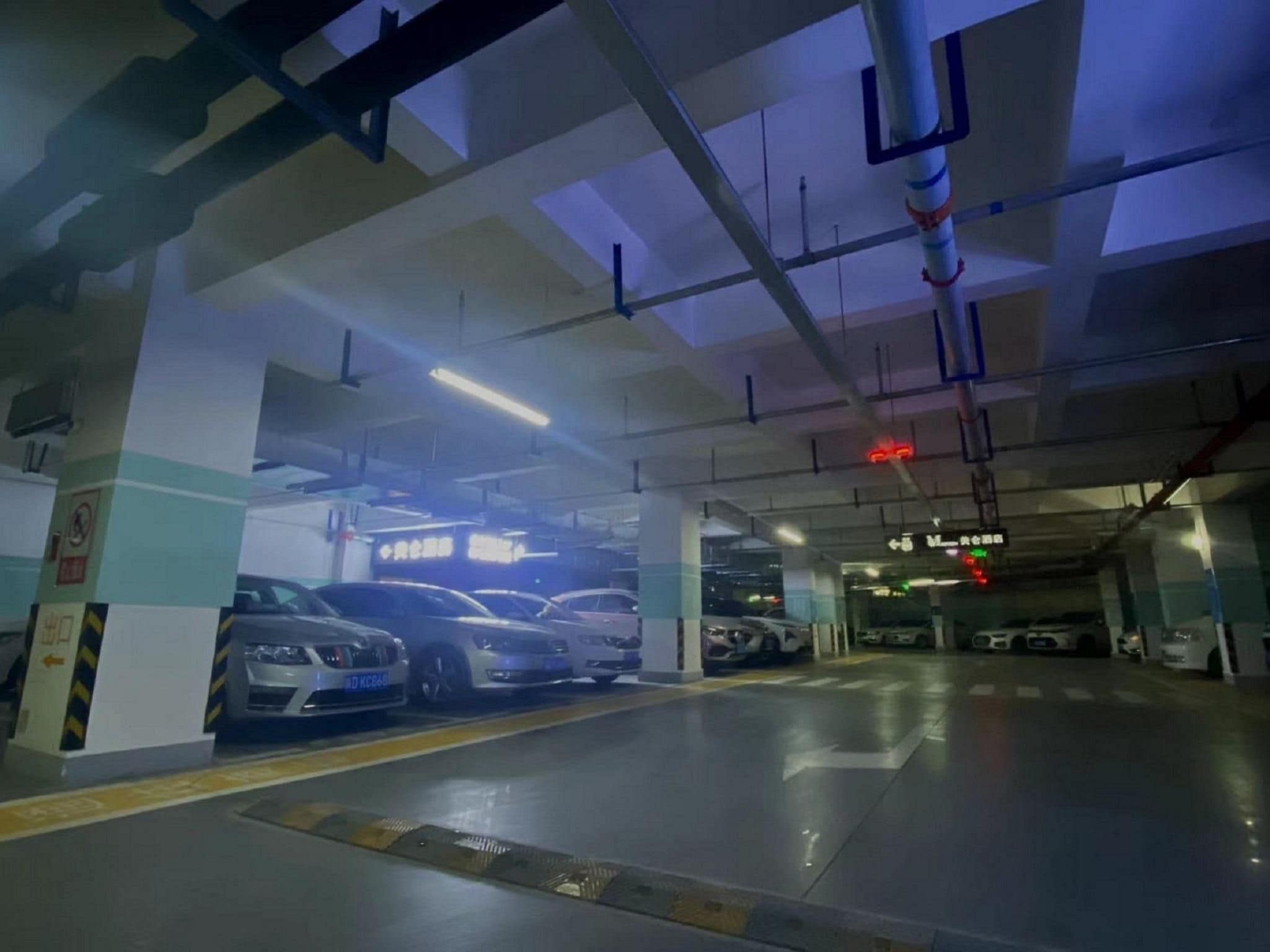 Un parcheggio sotterraneo su più livelli, segnalato da indicazioni chiare e frecce direzionali sul pavimento.