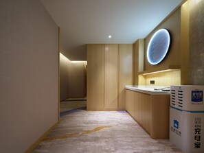 A hotel lobby with a reception desk, a wall-mounted circular light fixture, and a carpeted floor. - Madison Hotel Xianyang Zhuquan Road Wanda Plaza (Xianyang)