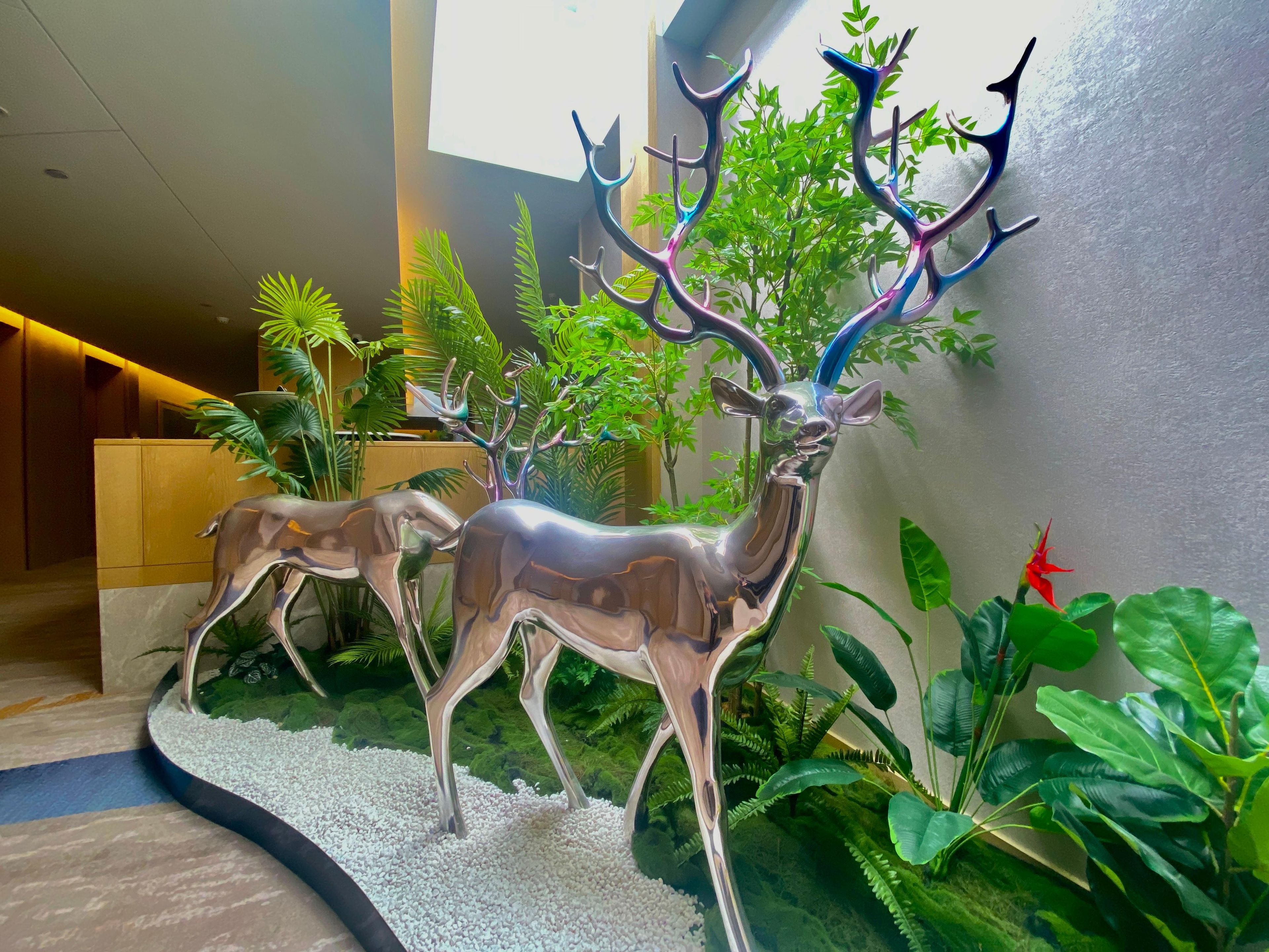 A reception area with a reception desk, a plant, and a decorative metal sculpture of deer.