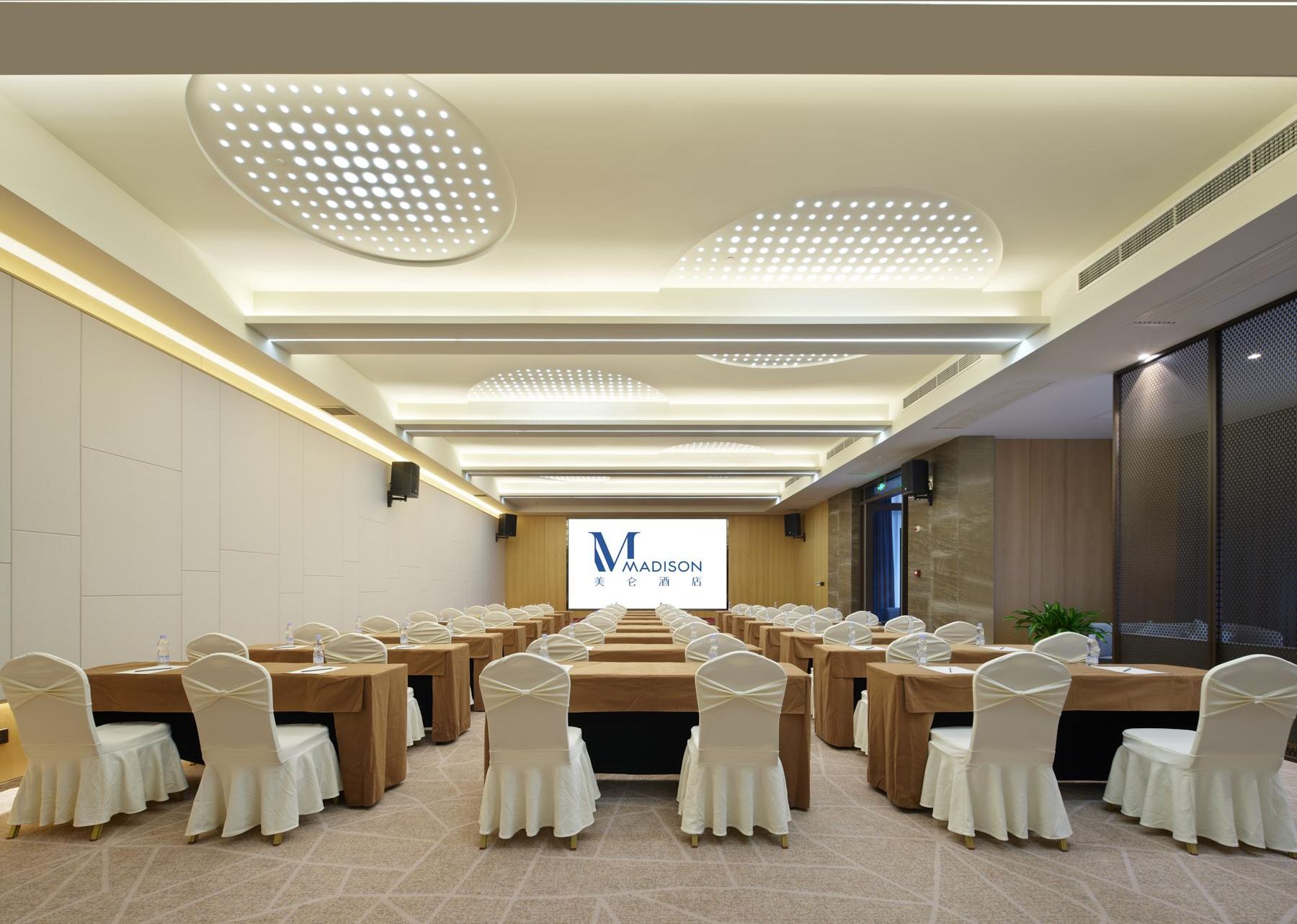 Une salle de conférence dotée de plusieurs tables et chaises, d’une enseigne portant l’inscription « MADISON » et des caractères chinois, et d’un design de plafond moderne.