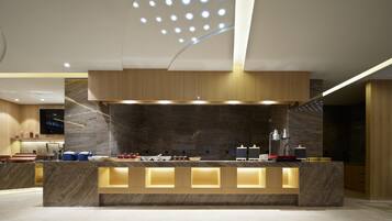 Una moderna reception con piano in marmo, illuminazione integrata e un soffitto ornato da un lampadario geometrico.