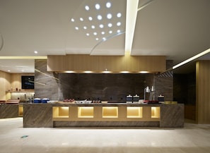 A modern reception desk with a marble countertop, integrated lighting, and a ceiling with a geometric light fixture. - Madison Hotel Xianyang Zhuquan Road Wanda Plaza (Xianyang)