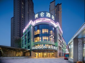Un hôtel moderne doté d’une façade incurvée, de grandes fenêtres et d’une enseigne lumineuse.