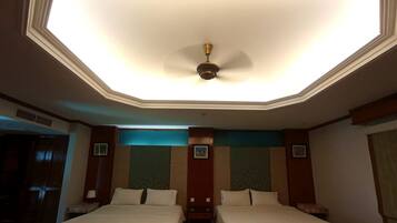 A hotel room with two beds, a ceiling fan, and a skylight.