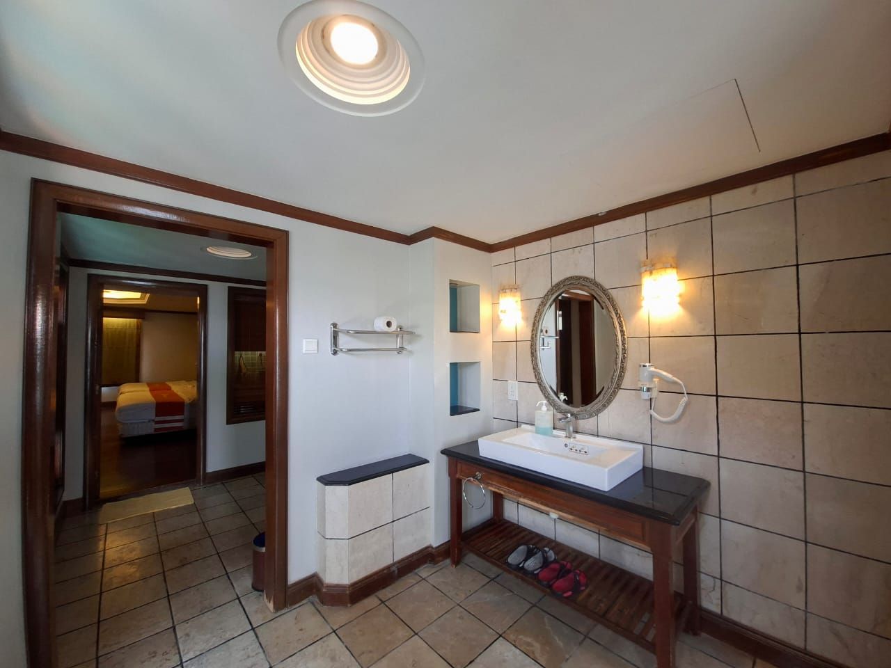 Un baño con lavamanos blanco, espejo y zona de ducha.