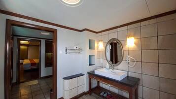 Un baño con lavamanos blanco, espejo y zona de ducha.