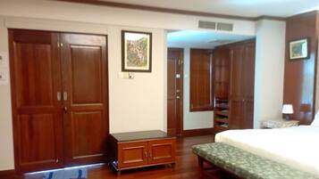 Un dormitorio con una cama, un banco de madera, un armario y una mesita de noche con una lámpara.