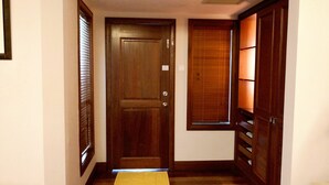A hallway with a wooden door, a window with blinds, and a wooden cabinet. - Alpine GLX Port Dickson (Port Dickson)