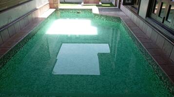 Una piscina con borde de azulejos y un objeto rectangular blanco en el centro.