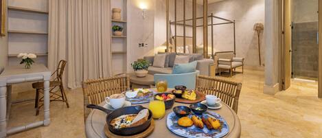 Un comedor con una mesa redonda dispuesta para el desayuno, un sofá y una zona de ducha.