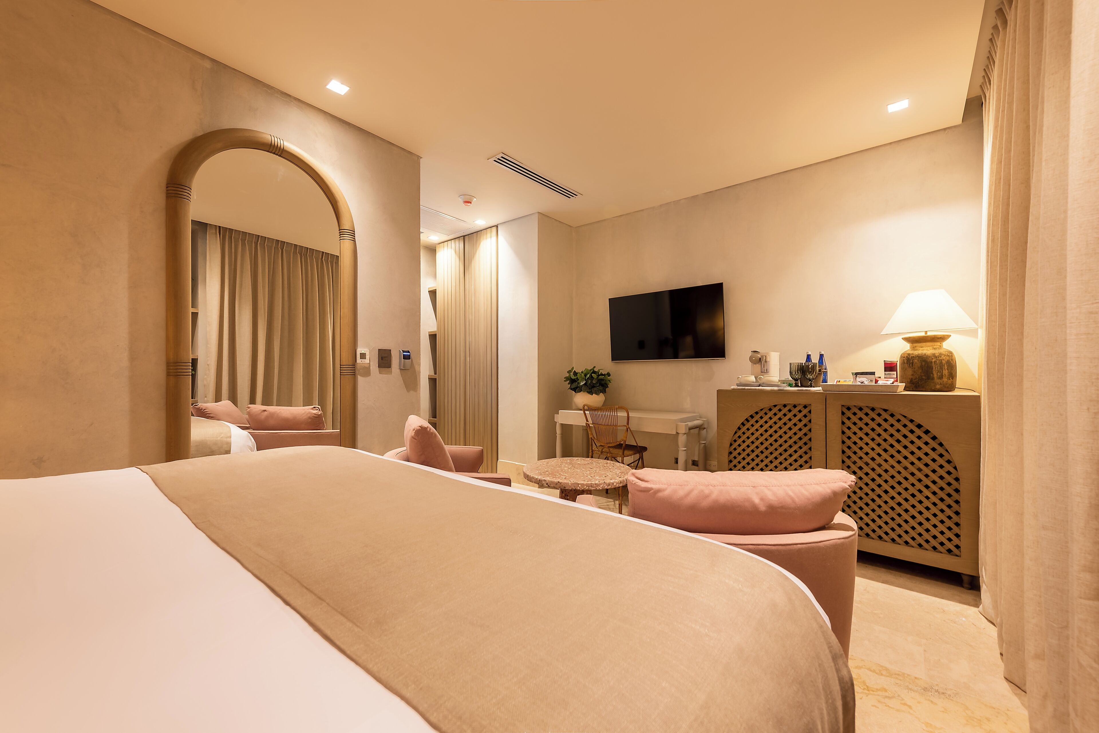 Una habitación de hotel con una cama grande, un escritorio con silla, un televisor y una lámpara.