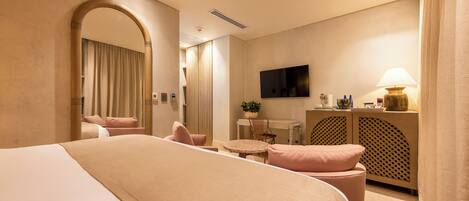 Una habitación de hotel con una cama grande, un escritorio con silla, un televisor y una lámpara.
