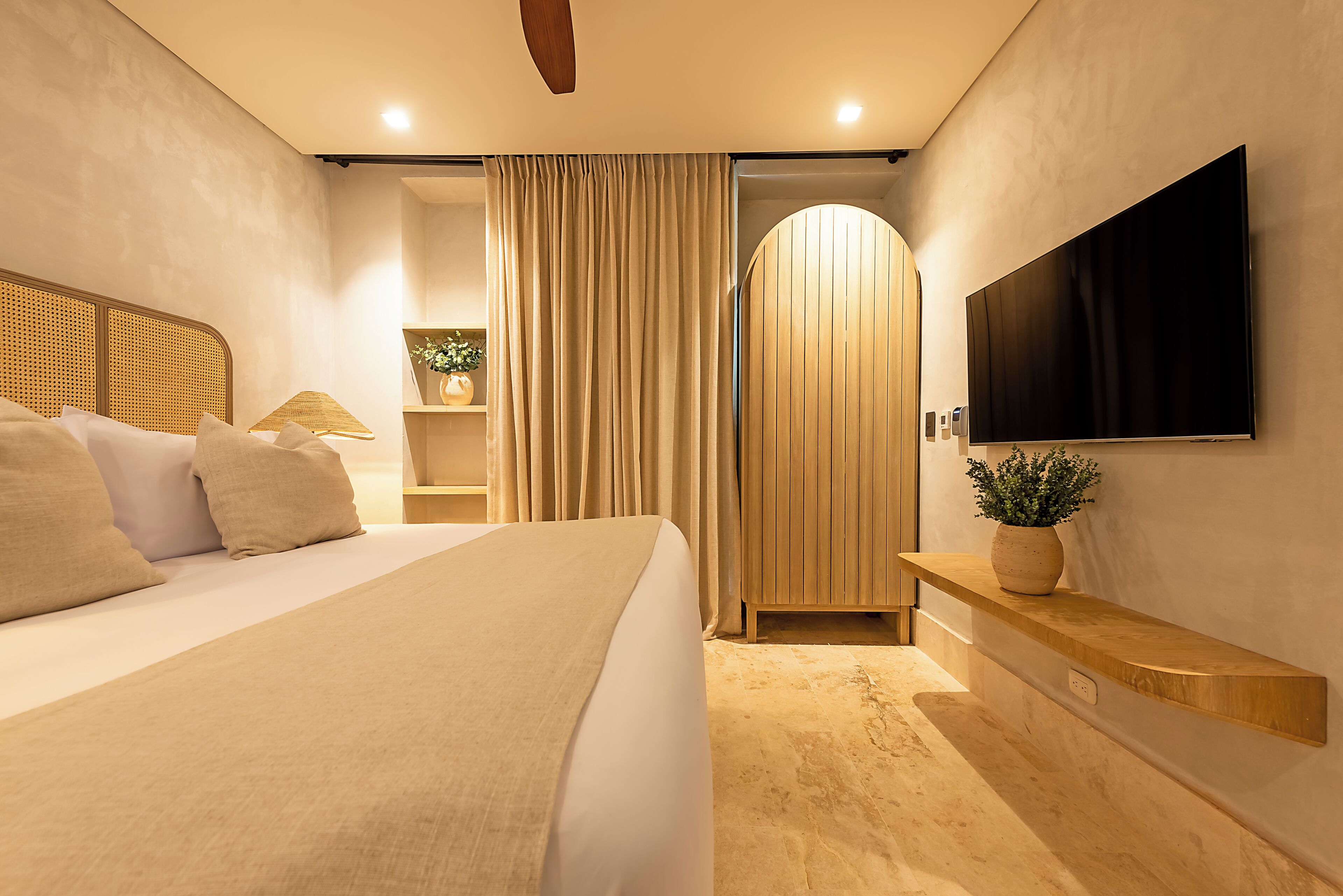 Ein modernes Hotelzimmer mit einem großen Bett, einem flachbildfernseher an der Wand und einer Holztür.