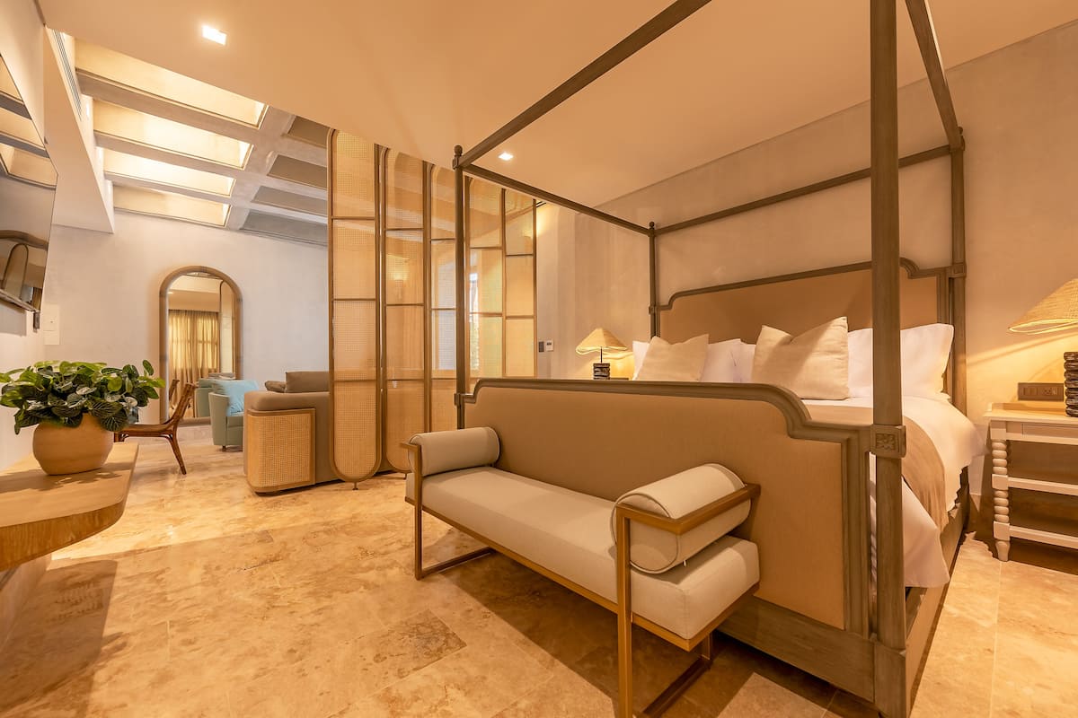 A modern bedroom with a four-poster bed, a sofa, and a large mirror.