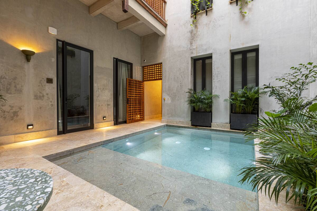 A modern indoor pool area with a clear pool, tiled flooring, and potted plants.
