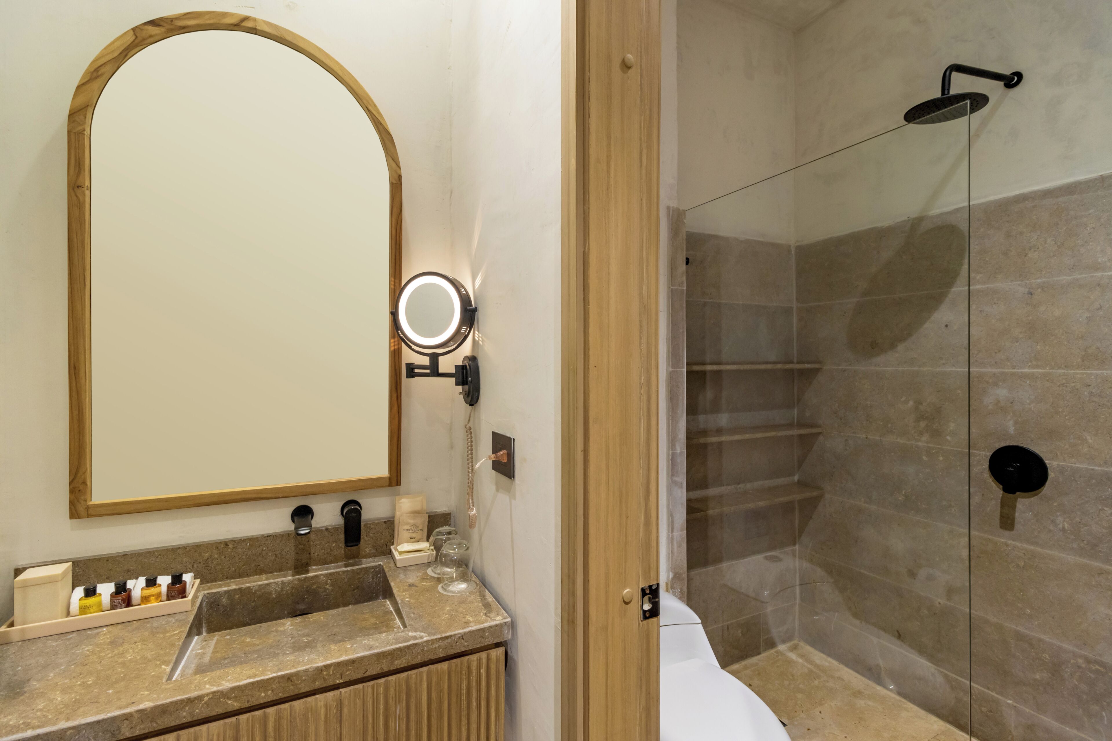 A bathroom with a vanity, a mirror, a shower, and a glass-enclosed shower stall.