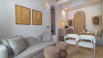 Una sala de estar moderna con un sofá, dos sillones, una mesita de centro y detalles decorativos de madera en la pared.