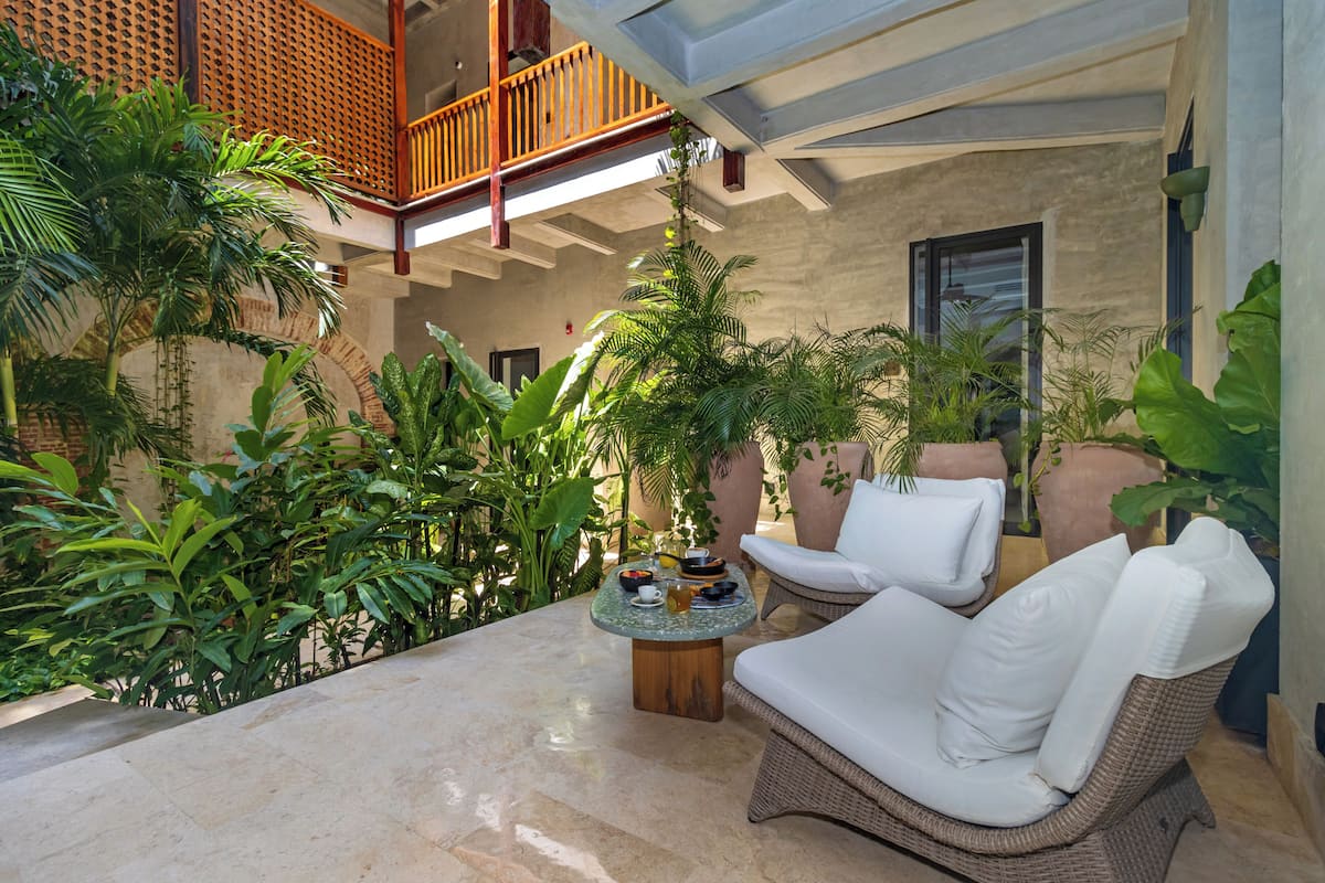 A patio with a wicker sofa, a round table, and various plants.