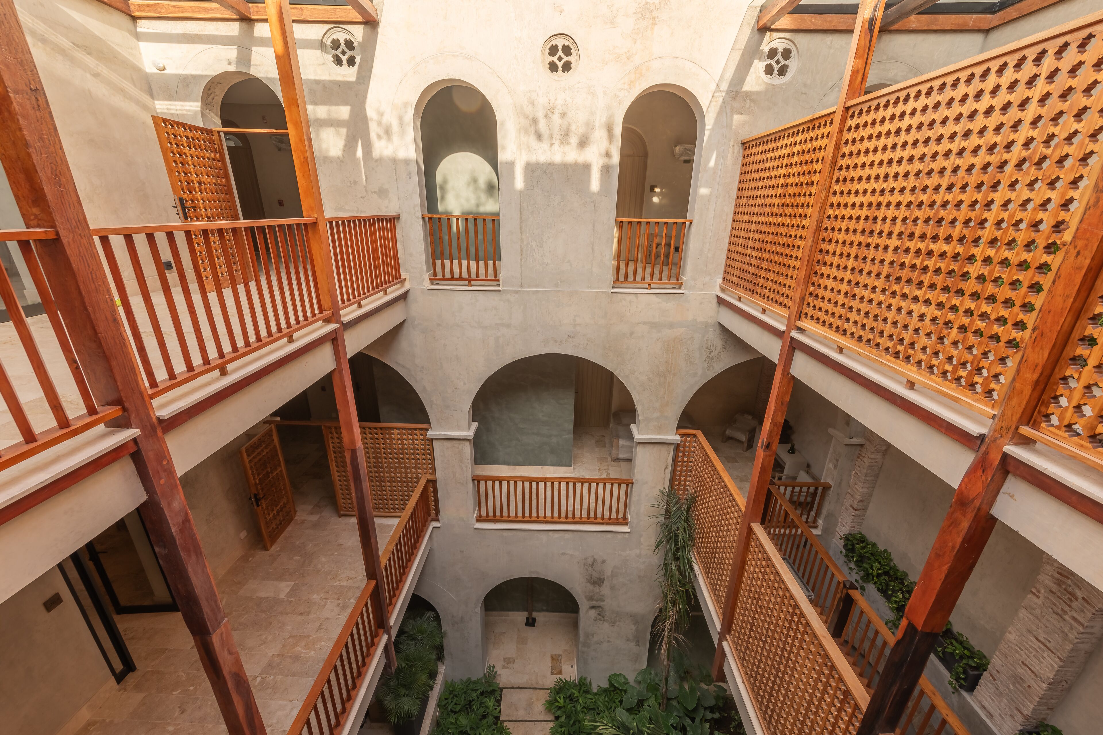 Un cortile a più livelli con ringhiere in legno e aperture ad arco.