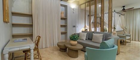 A modern living room with a sofa, two round coffee tables, a dining table with chairs, and a hanging light fixture.
