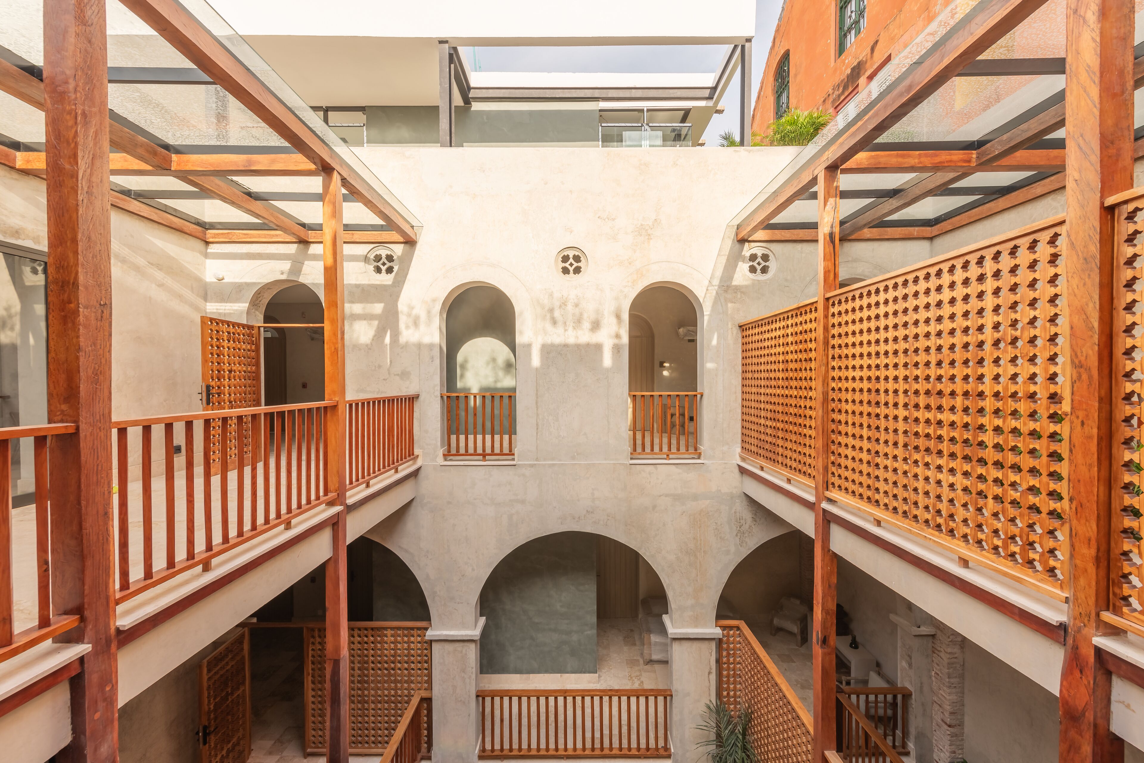 A courtyard with wooden balconies, arched doorways, and a lattice wall.