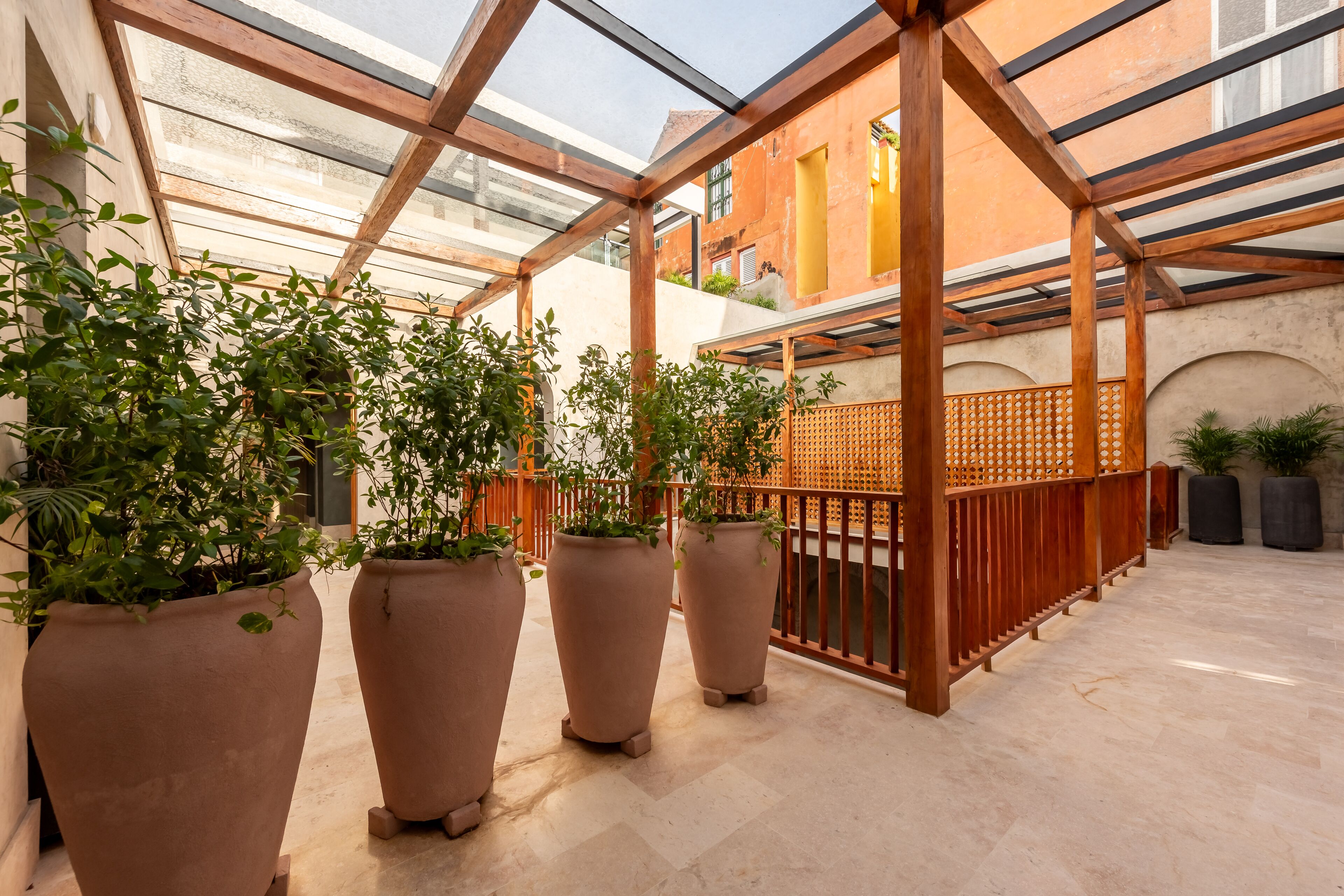 Uma área externa coberta com vasos de terracota e uma estrutura de pérgola de madeira.