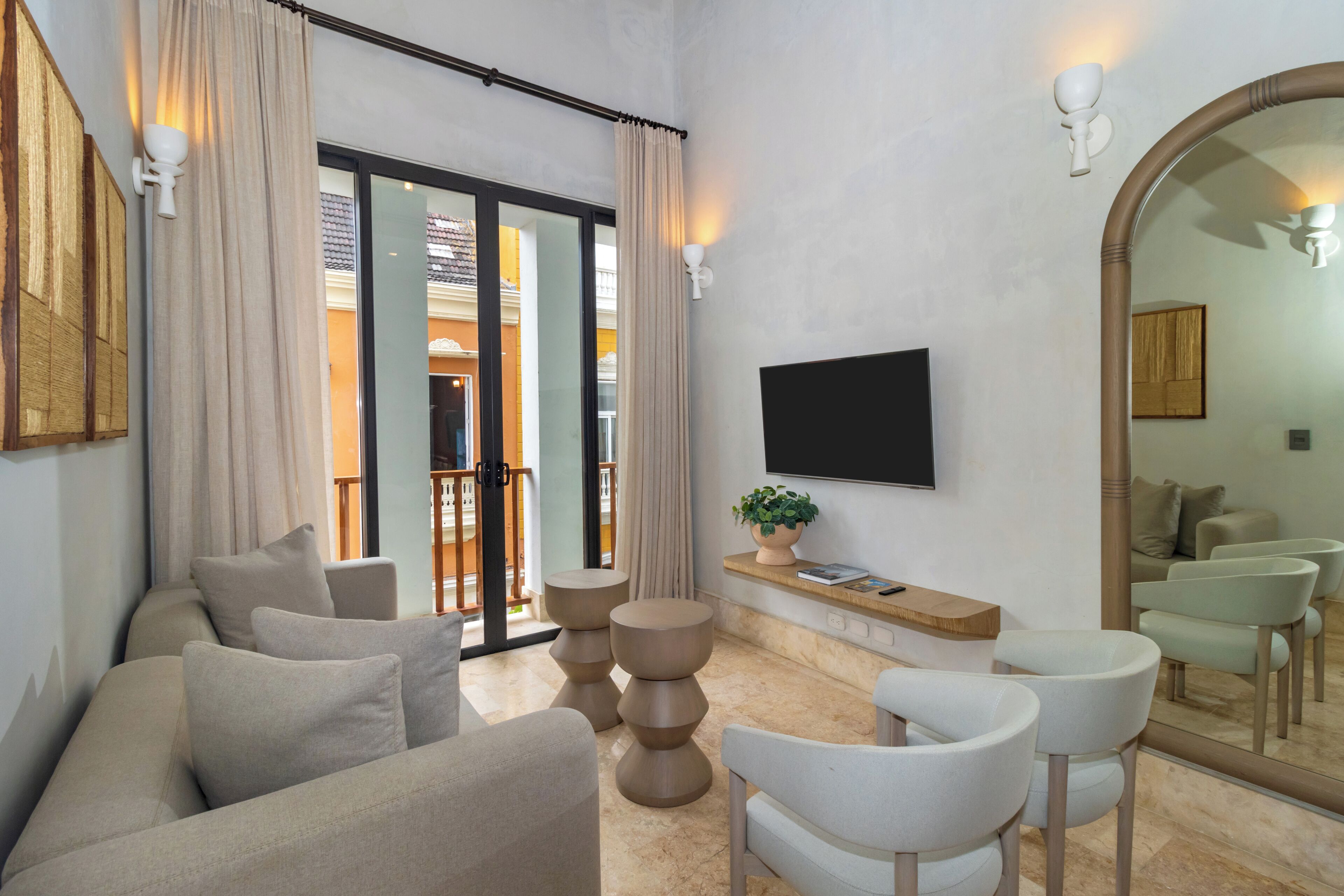 A modern living room with a sofa, armchairs, a coffee table, a TV, and a large mirror.