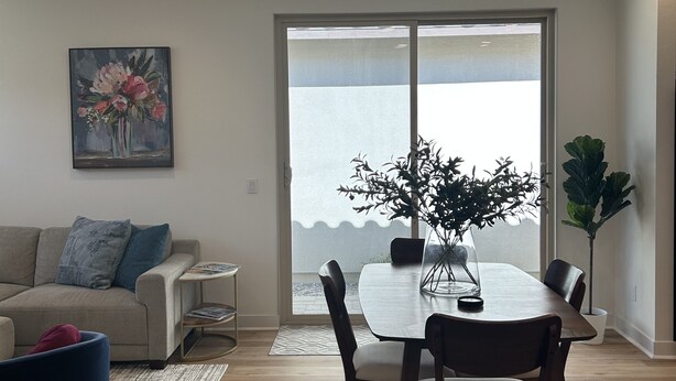 A modern living room with a dining area, a sofa, a coffee table, and a large window with a view. - PGA WEST Whisper Rock #254648 (La Quinta)