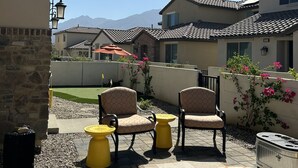 A patio area with outdoor seating, a stone wall, and a view of a mountain range. - PGA WEST Whisper Rock #254648 (La Quinta)