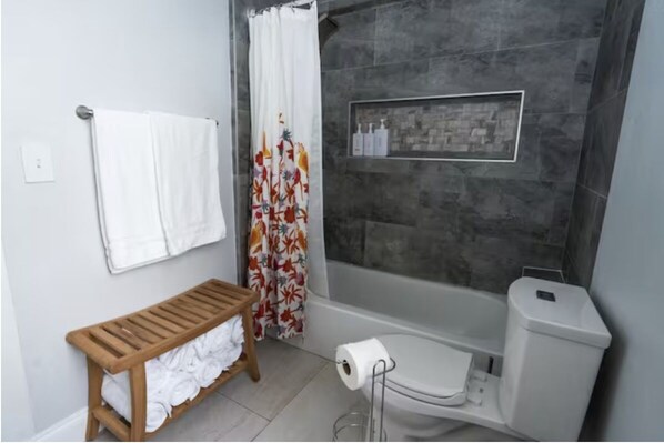 Une salle de bain avec une douche, des toilettes et un banc avec des serviettes.