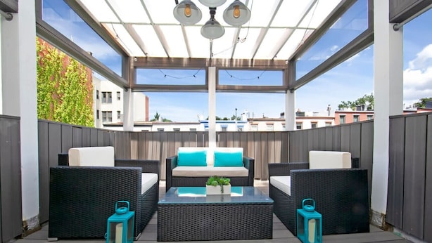An outdoor patio with wicker furniture, a glass-top table, and a ceiling with pendant lights. - Centralized apt in Park Slope near the park and the city (Brooklyn)