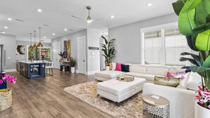 A spacious living room with a white sofa, a coffee table, and a large plant.
