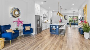 A modern kitchen with white cabinetry, a stainless steel refrigerator, and a blue island.