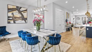 A modern dining area with a white table, blue chairs, and a vase of flowers.