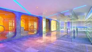 A modern hotel lobby with glass walls, a seating area with a circular bench, and a reception desk.