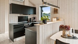 Una cocina moderna con paneles de madera, un ventanal grande y un comedor con una mesa y sillas blancas.