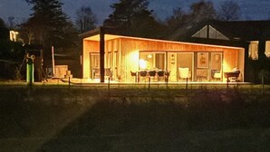 Een modern huis met een grote glazen deur, een eetgedeelte met stoelen en een klein terras.