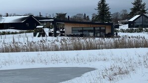 Een modern gebouw met een grote glazen gevel, omgeven door met sneeuw bedekte velden en bomen.